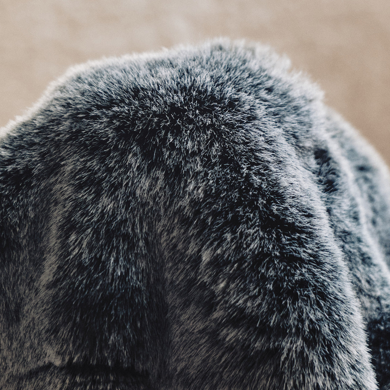 A muted gray-to-black design with a chunky knit texture, frayed edges, and a casual draped style, offering relaxed sophistication.