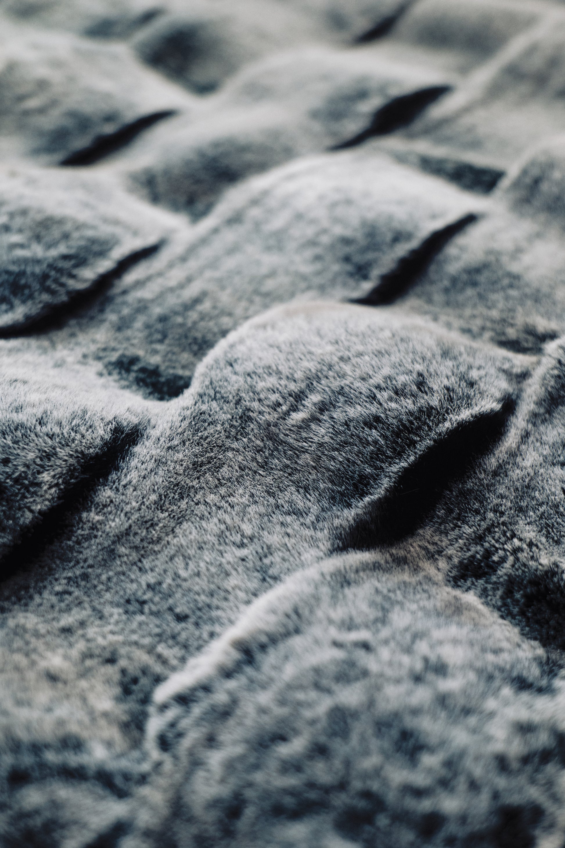 A dramatic gradient blanket in deep obsidian hues, textured with undulating 3D waves and a matte-sheen finish, ideal for contemporary interiors.
