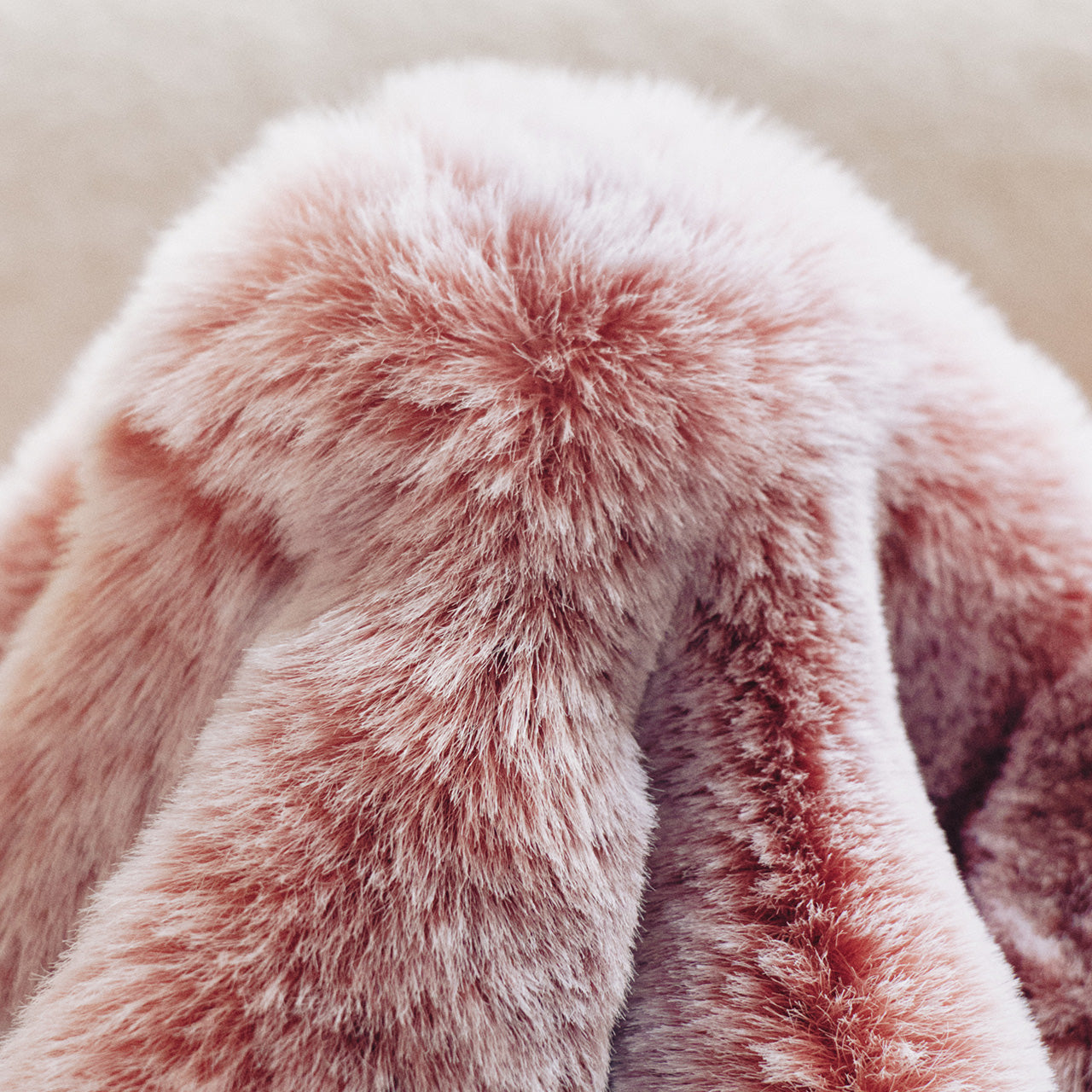 A muted pink gradient blanket with a linen-textured weave, minimalist folds, and neutral taupe stitching, blending understated luxury with bohemian charm.
