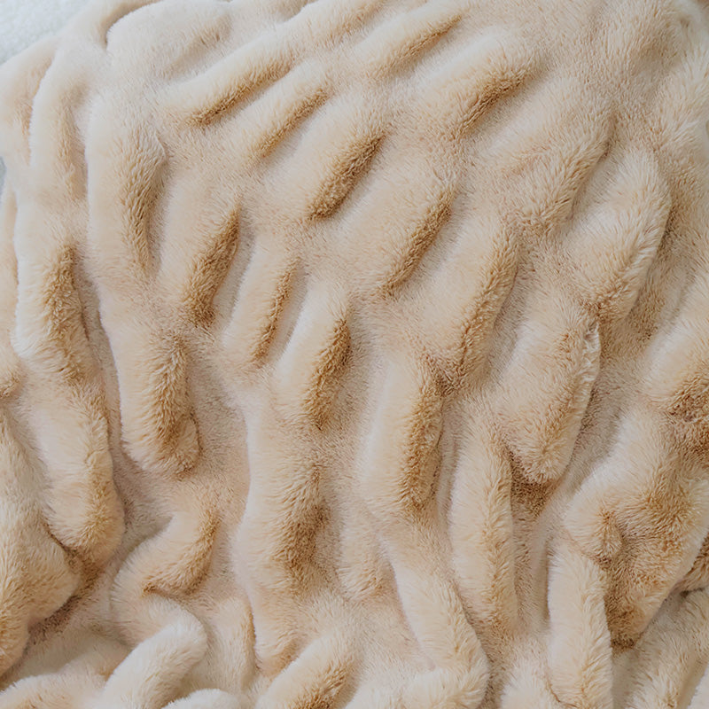 A close-up of a plush, textured beige fabric with elongated parallel ridges forming a wavy pattern. The material has a soft, creamy color with subtle shading variations along the ridges, creating a sense of depth.