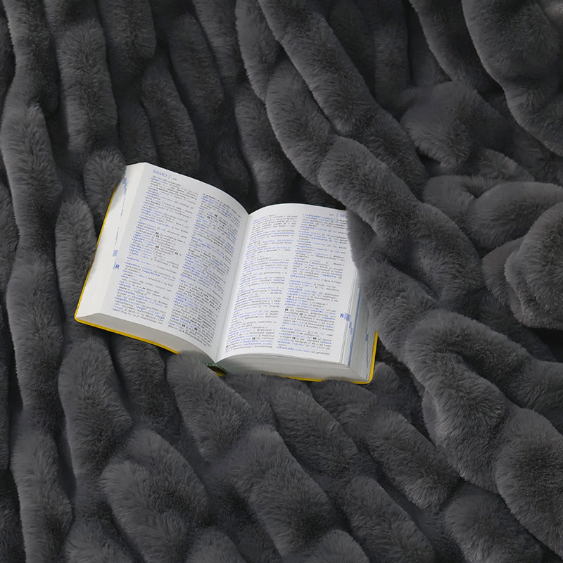 An open book with text in two columns rests on a textured dark gray fluffy surface.