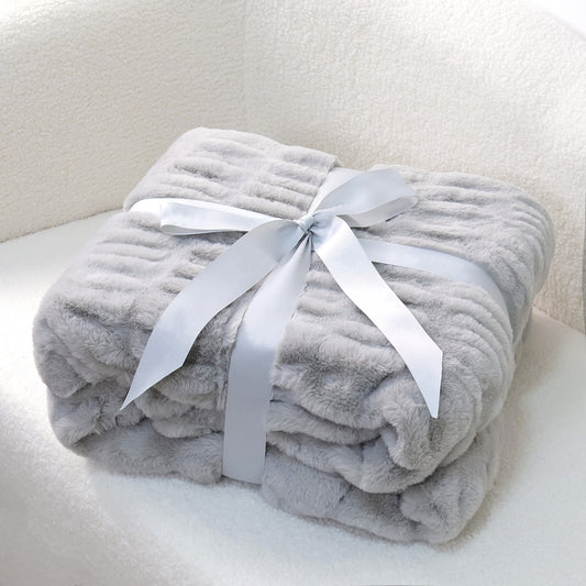 A folded gray textured blanket tied with a white satin ribbon on a white surface.