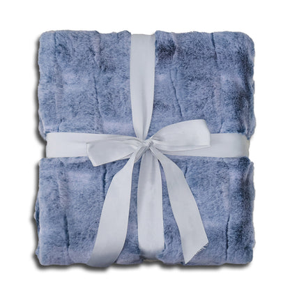A folded soft blue velvet blanket with subtle surface texture, elegantly decorated with a white ribbon tied into a bow at the center. The clean white background highlights the harmonious blue-and-white color palette, evoking a sense of calmness, warmth, and timeless elegance.