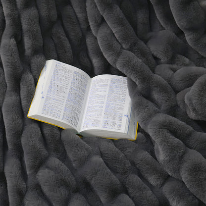 An open book with text in two columns rests on a textured dark gray fluffy surface.